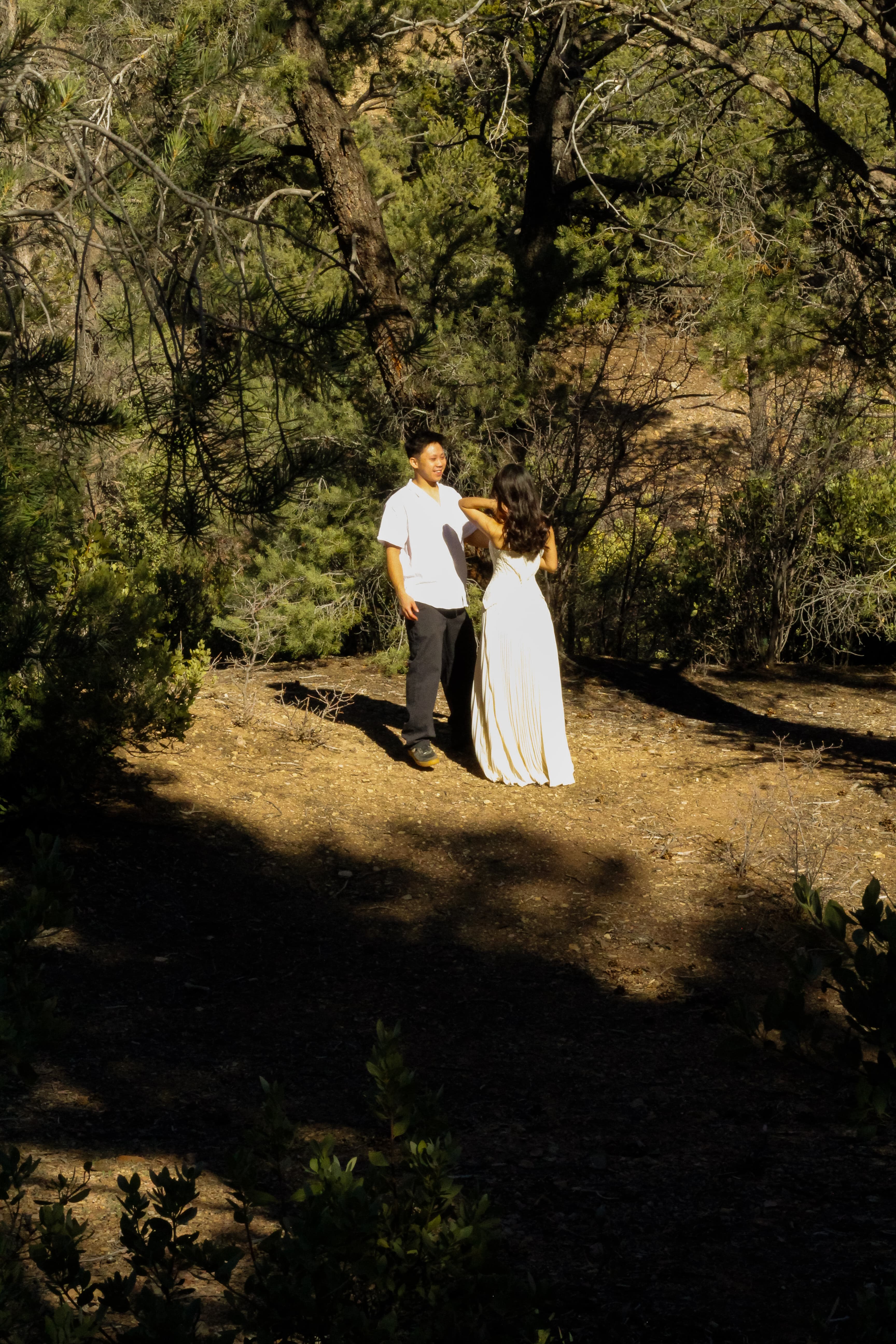 Drazy and Lupe standing together beneath desert pines